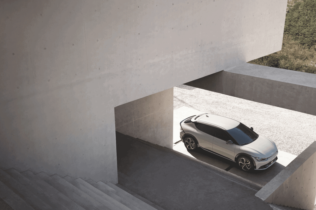 Coche eléctrico estacionado en un garaje minimalista de concreto, con diseño arquitectónico limpio y.