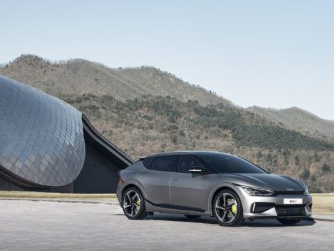 Coche eléctrico deportivo gris en un paisaje montañoso y moderno.