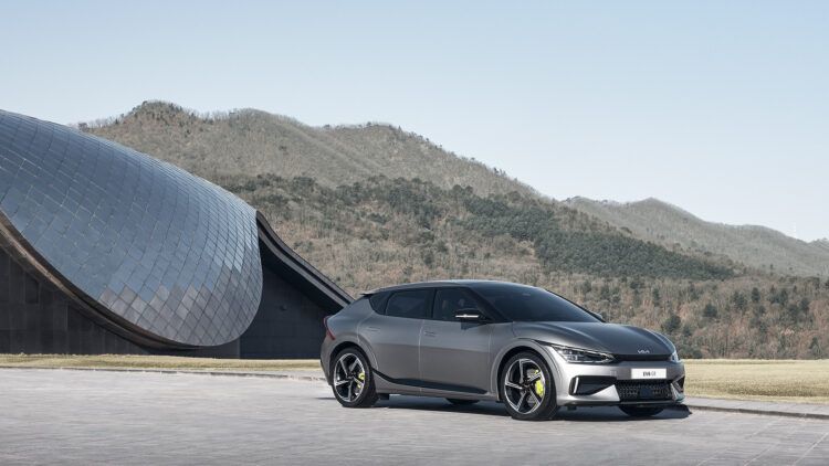 Coche eléctrico deportivo gris en un paisaje montañoso y moderno.