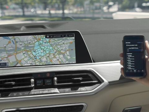 Navegación en coche eléctrico con pantalla y teléfono móvil en el interior del vehículo.