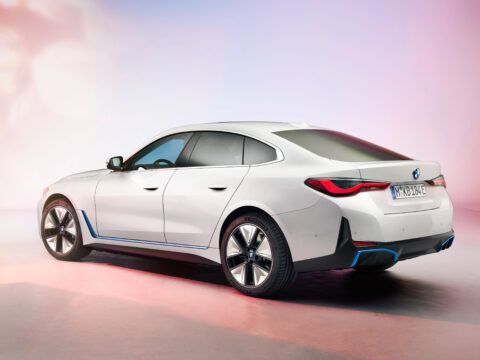 Coche eléctrico moderno en color blanco con diseño aerodinámico y detalles en azul, en un fondo con.