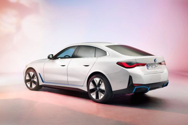 Coche eléctrico moderno en color blanco con diseño aerodinámico y detalles en azul, en un fondo con.