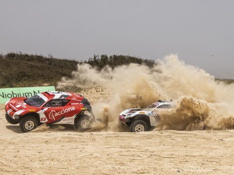 Líderes en rally raid en un terreno arenoso con polvo y tierra en el aire.