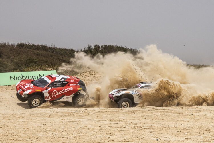 Líderes en rally raid en un terreno arenoso con polvo y tierra en el aire.