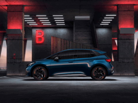 Coche eléctrico azul estacionado en un entorno urbano con iluminación moderna y señal de "B" en el f.
