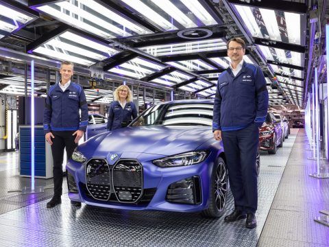 Personal de fábrica inspeccionando coche eléctrico en línea de ensamblaje moderna.