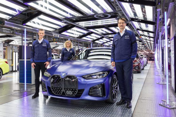 Personal de fábrica inspeccionando coche eléctrico en línea de ensamblaje moderna.