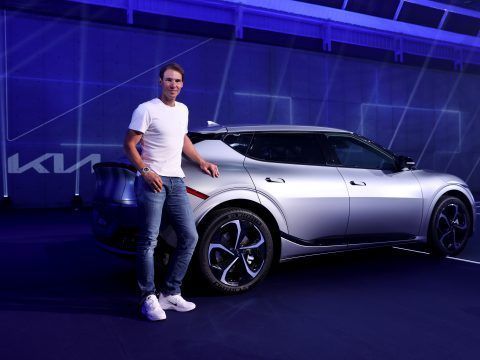 Tesla Model Y eléctrico en exhibición con un hombre sonriendo al lado.
