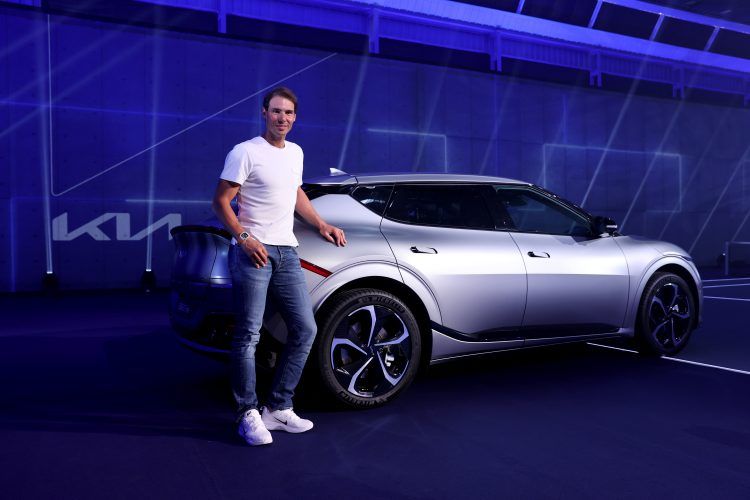 Tesla Model Y eléctrico en exhibición con un hombre sonriendo al lado.