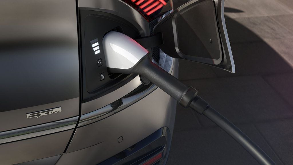 Cargador de coche eléctrico conectado a un vehículo en una estación de carga.