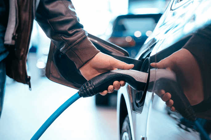 Carga de coche eléctrico en estación de carga rápida.