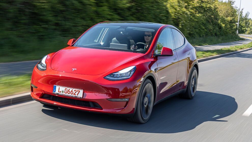 Tesla Model 3 en movimiento en carretera, coche eléctrico de diseño aerodinámico y tecnología avanza.