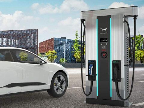 Cargador de coches eléctricos en ciudad moderna con vehículo eléctrico conectado, promoviendo movili.