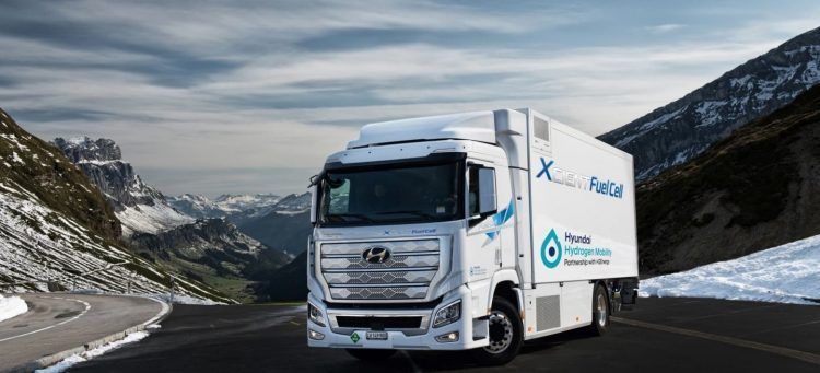 El camión eléctrico de Hidrógeno HYUNDAI XCIENT Fuel Cell Camión eléctrico en carretera montañosa con paisaje de picos nevados y cielo nublado.