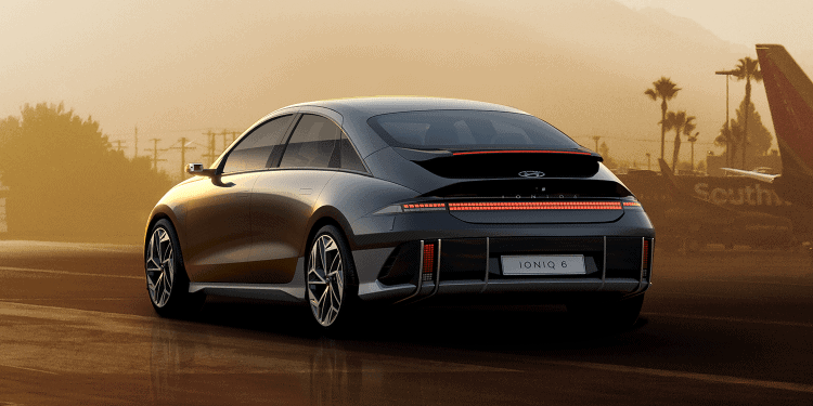 Coche eléctrico de diseño moderno en un aeropuerto durante el atardecer, resaltando innovación y mov.