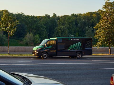 Camión eléctrico de reparto en la carretera con fondo de árboles y cielo despejado.