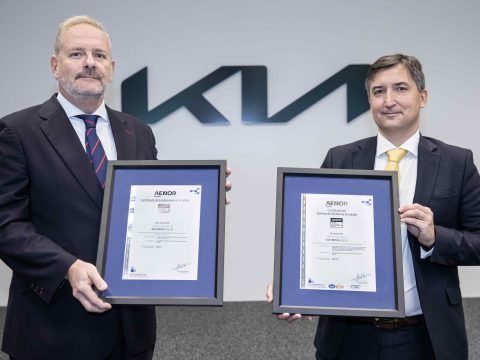 Dos ejecutivos sosteniendo certificados de reconocimiento en un evento de movilidad eléctrica.