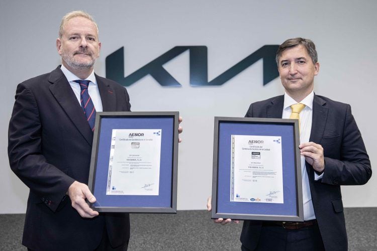 Dos ejecutivos sosteniendo certificados de reconocimiento en un evento de movilidad eléctrica.