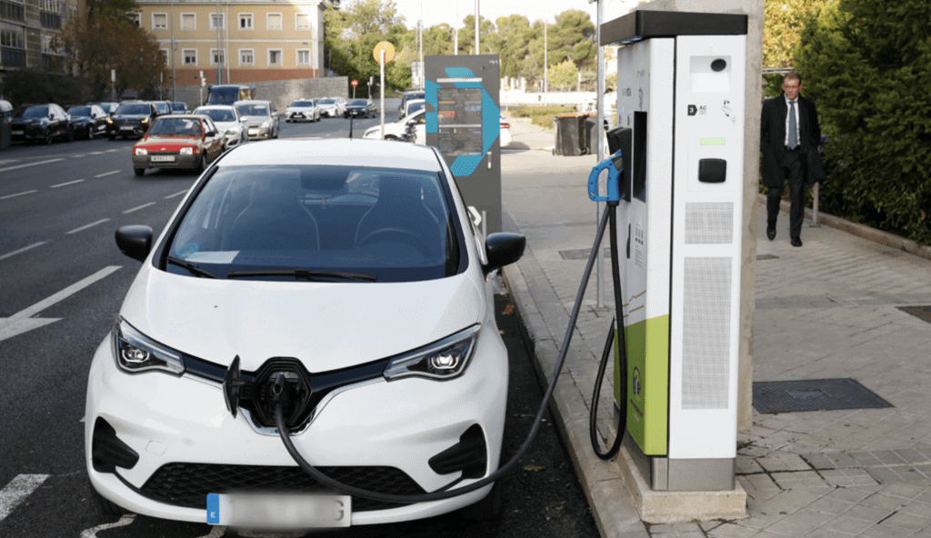 Coche eléctrico cargando en estación de recarga en la ciudad.