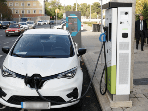 Coche eléctrico cargando en estación de recarga en la ciudad.