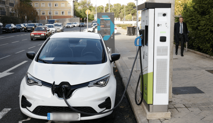 Coche eléctrico cargando en estación de recarga en la ciudad.