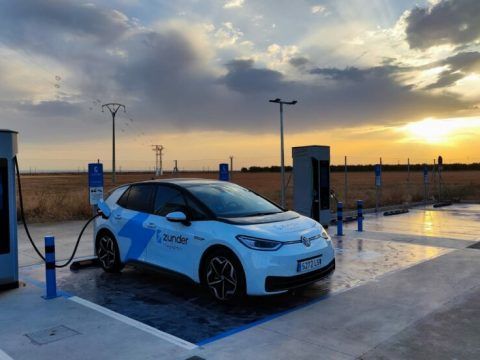 Coche eléctrico cargando en estación de recarga al atardecer, energía limpia y movilidad sostenib.
