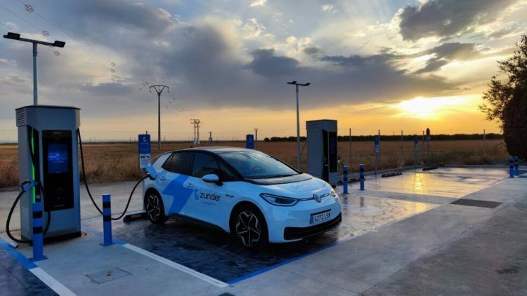 Coche eléctrico cargando en estación de recarga al atardecer, energía limpia y movilidad sostenib.