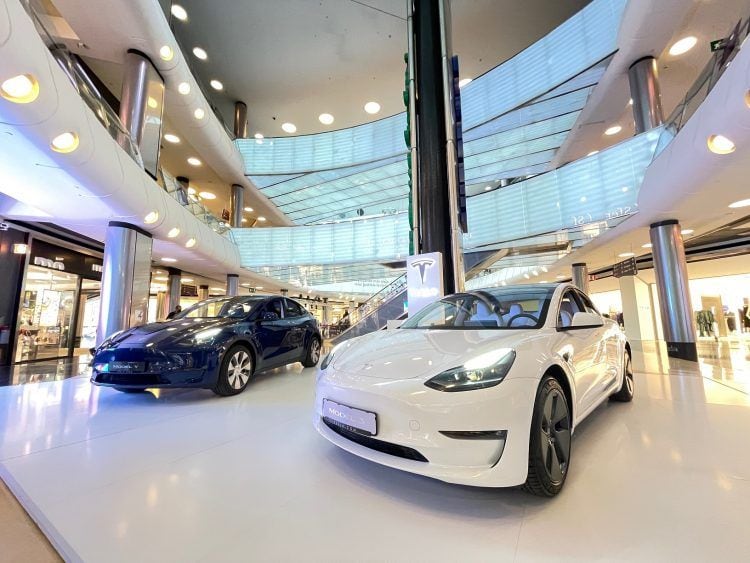 Coches eléctricos en exhibición en un centro comercial moderno y luminoso.
