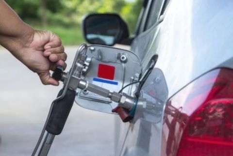 Persona conectando un coche eléctrico a una estación de carga en exteriores.