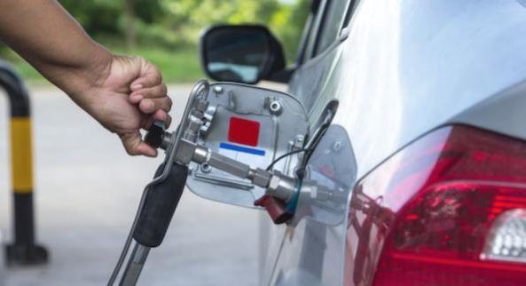 Persona conectando un coche eléctrico a una estación de carga en exteriores.