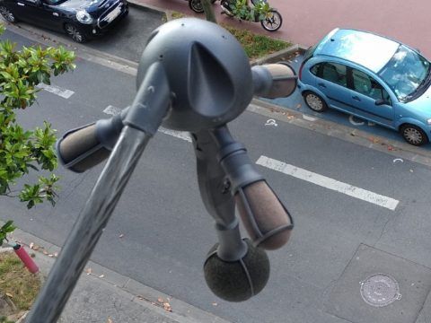 Cargador de coche eléctrico en la vía pública, conectado a un vehículo azul.