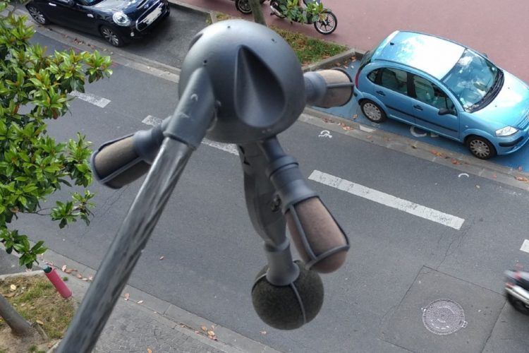 Cargador de coche eléctrico en la vía pública, conectado a un vehículo azul.