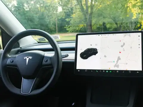 Interior de un coche eléctrico Tesla con volante y pantalla táctil de navegación en el tablero.