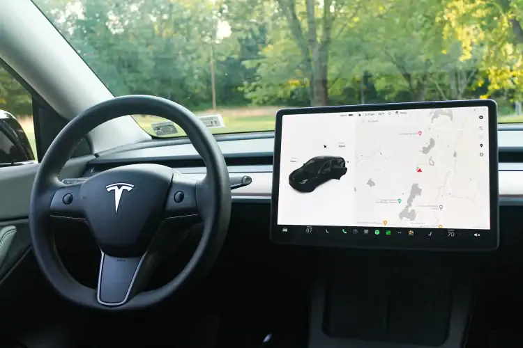 Interior de un coche eléctrico Tesla con volante y pantalla táctil de navegación en el tablero.