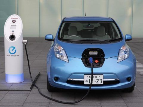 Coche eléctrico azul cargando en estación de recarga de vehículos eléctricos.