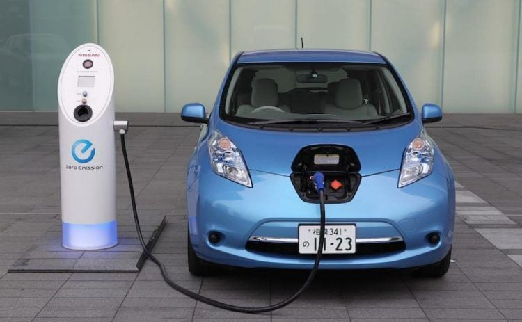 Coche eléctrico azul cargando en estación de recarga de vehículos eléctricos.