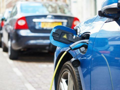 Coche eléctrico conectado a una estación de carga en la vía pública.