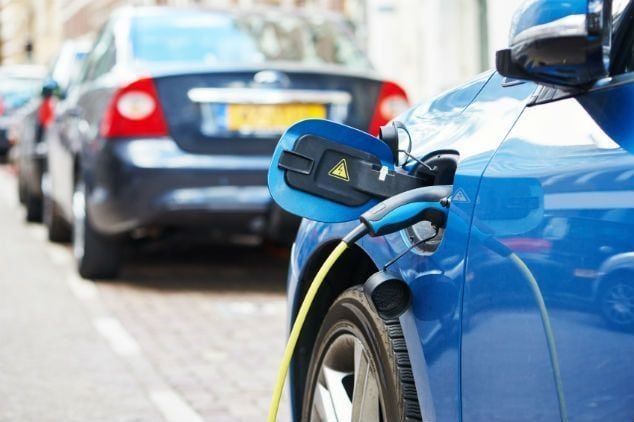 Coche eléctrico conectado a una estación de carga en la vía pública.