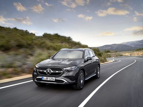 Coche eléctrico Mercedes-Benz conduciendo por una carretera curva en un paisaje montañoso.