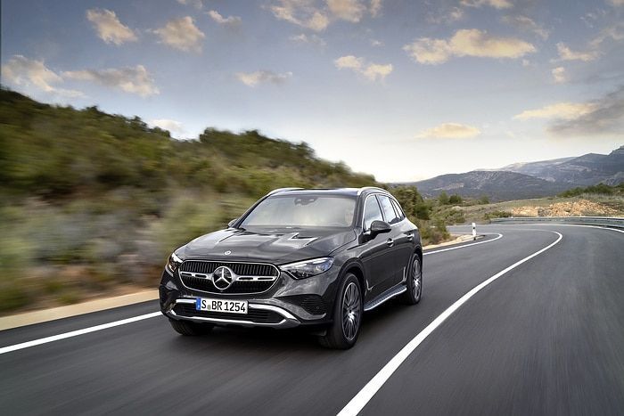 Coche eléctrico Mercedes-Benz conduciendo por una carretera curva en un paisaje montañoso.