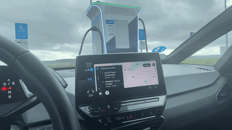 Cargador de coche eléctrico en ruta con pantalla digital y conectores en un coche en movimiento.