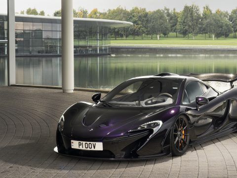 Coche deportivo eléctrico negro con spoiler en entorno urbano moderno.