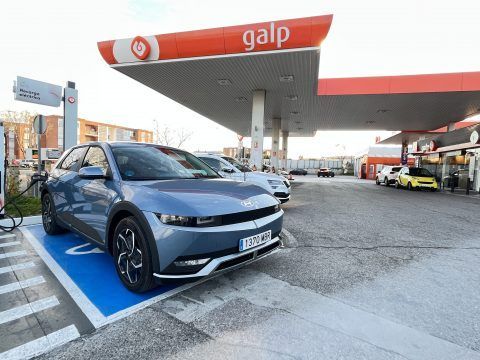 Coche eléctrico cargando en estación de carga rápida en un área de movilidad sostenible.