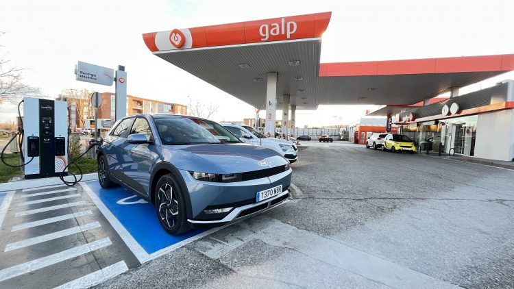 Coche eléctrico cargando en estación de carga rápida en un área de movilidad sostenible.