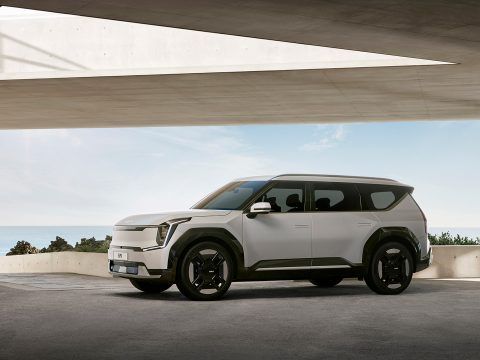 Coche eléctrico de diseño futurista en un entorno urbano con vista al mar.