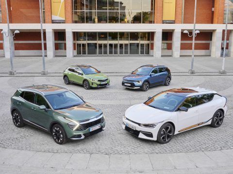 Cinco coches eléctricos en exhibición en una plaza urbana moderna.