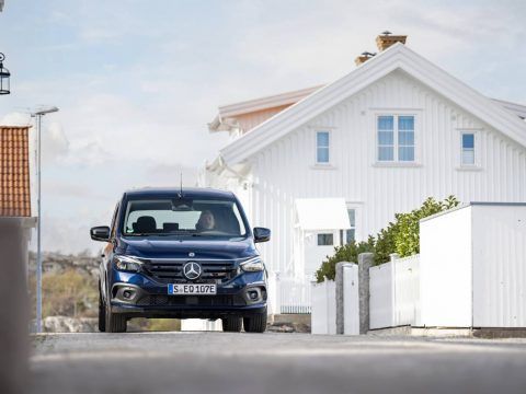 Coche eléctrico Mercedes-Benz estacionado frente a una casa moderna en un barrio tranquilo.