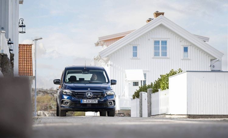 Coche eléctrico Mercedes-Benz estacionado frente a una casa moderna en un barrio tranquilo.