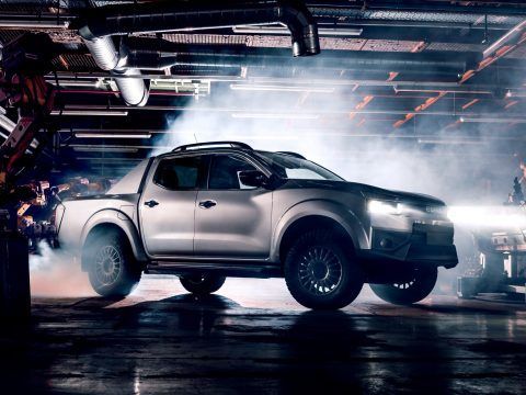 Un coche eléctrico futurista en un taller de fabricación con humo y luces de neón.