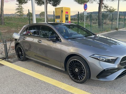 Coche eléctrico de color gris en estación de carga rápida, preparado para recargar energía en un pun.